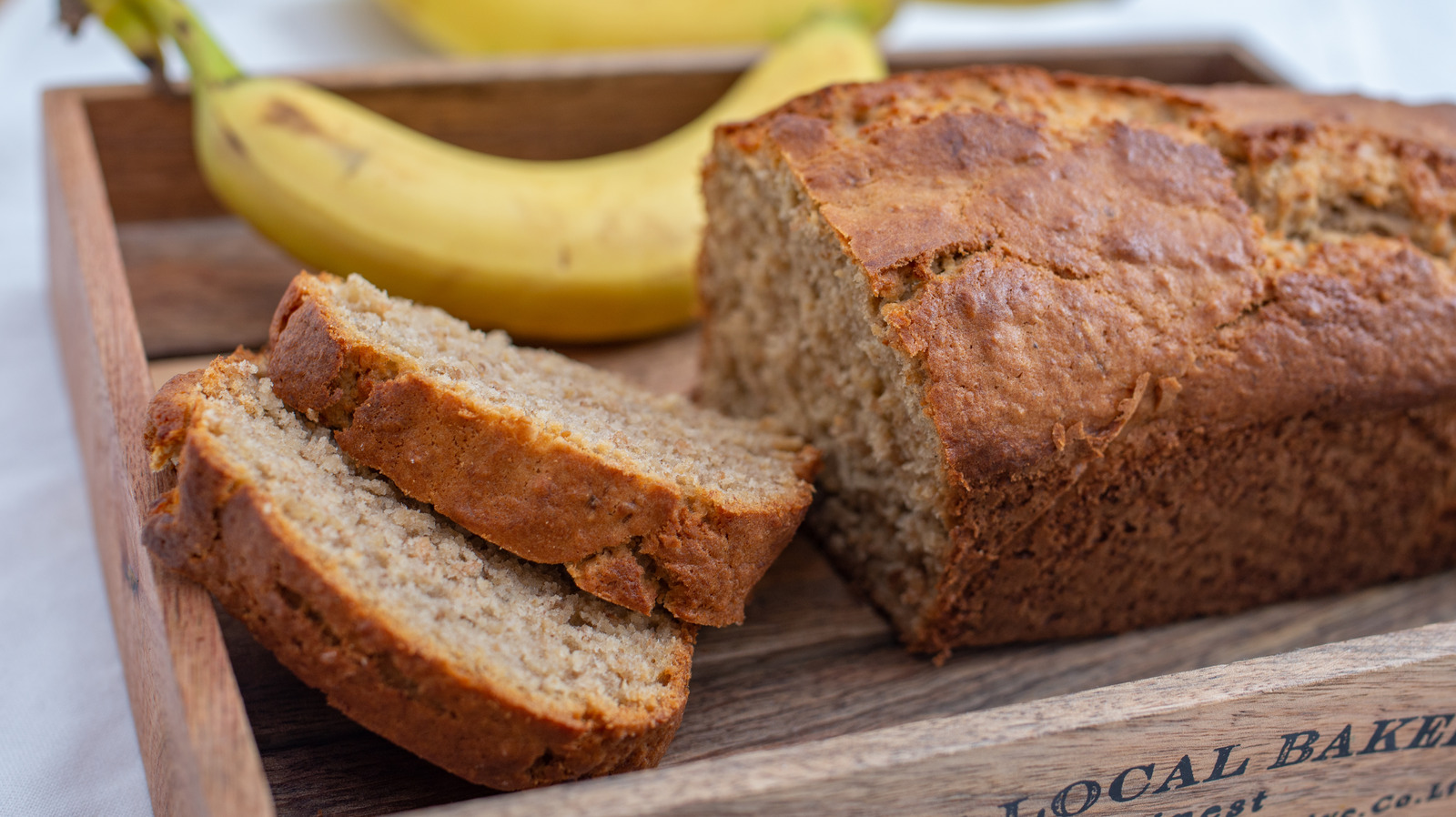 Banana bread studded with chopped walnuts on a rustic plate, surrounded by scattered nuts.